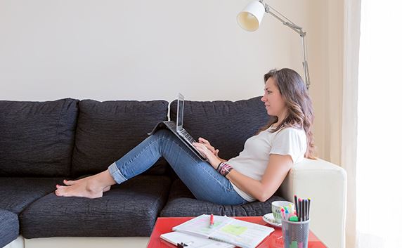 woman sitting on couch working on laptop