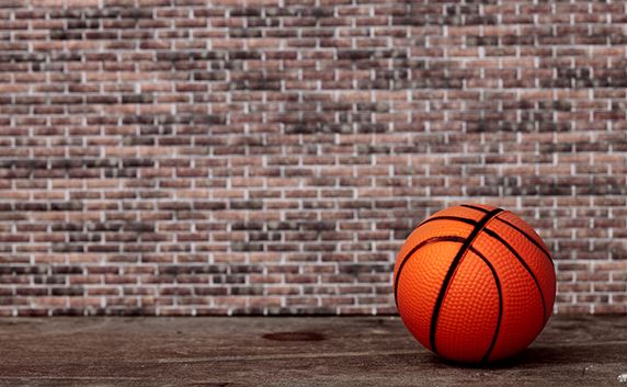 basketball on floor in front of brick wall