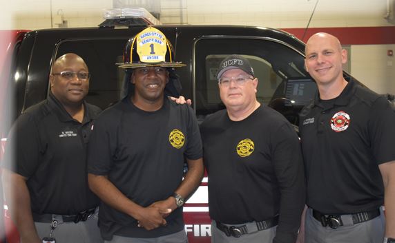 Andre Horton wearing vintage firefighter helmet surrounded by Fire Department Staff