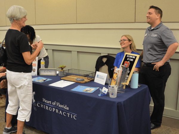 woman talking to two people standing next to a table with a black table cloth