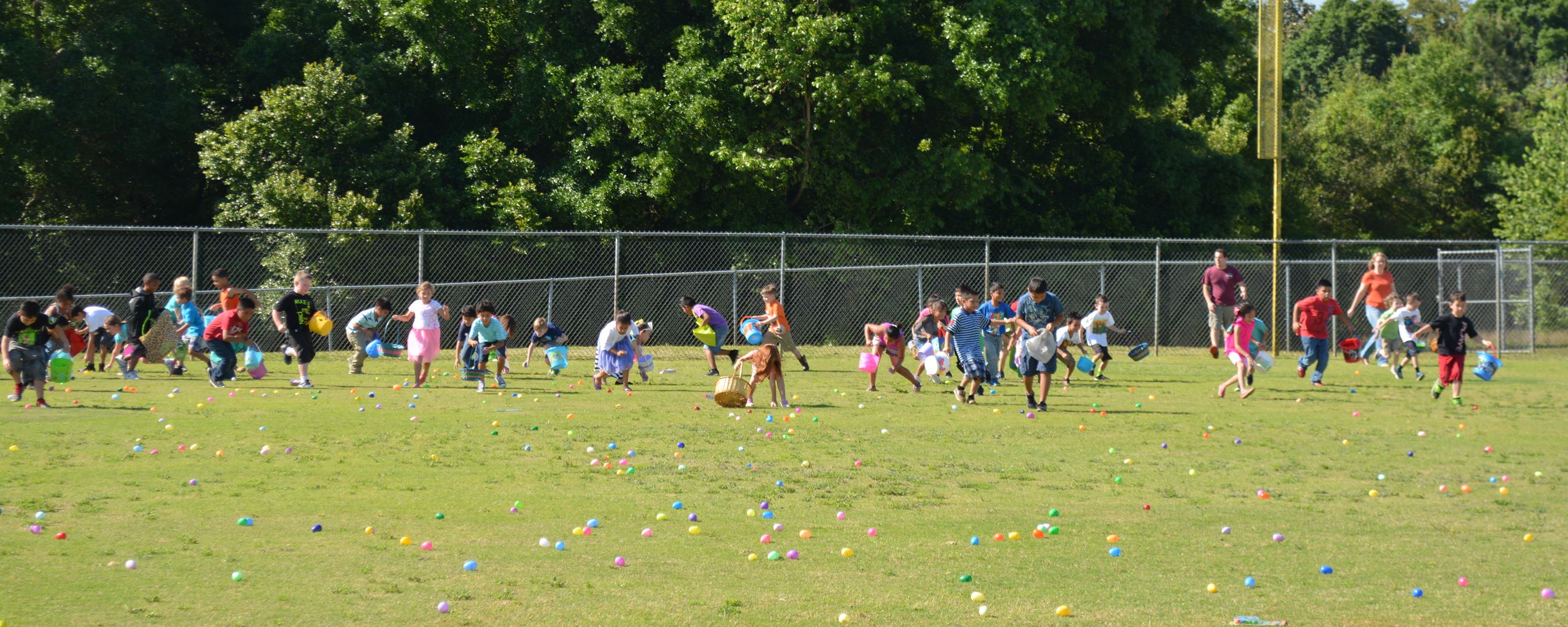 Kids gathering Easter eggs out on the field. (image)
