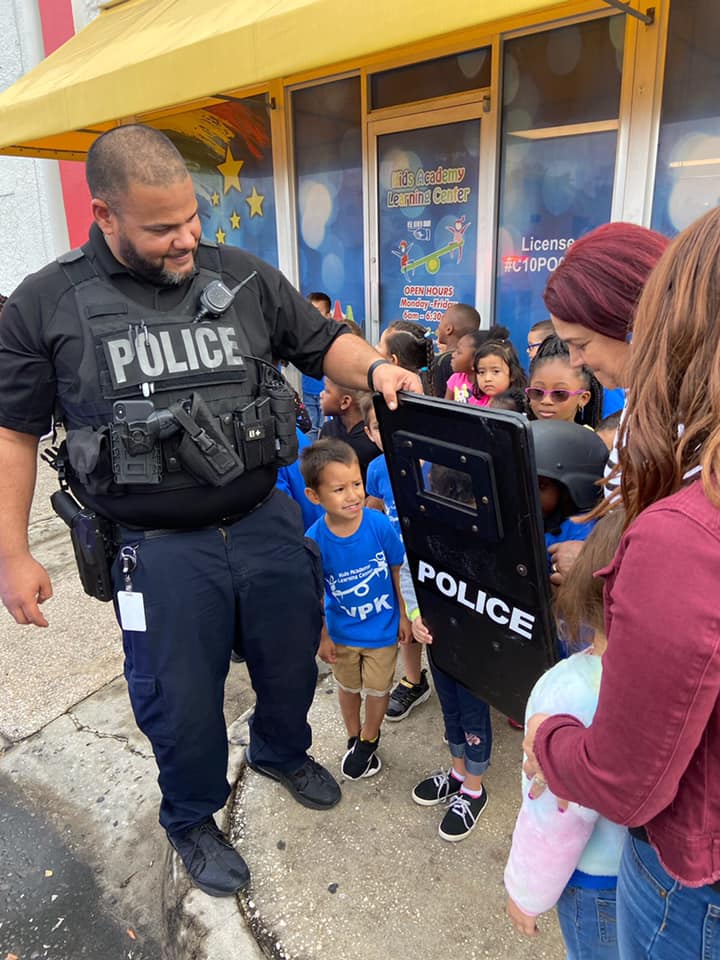 Officer Carlos Dominguez presents a law enforcement shield to youngsters at Kids First Academy Learn