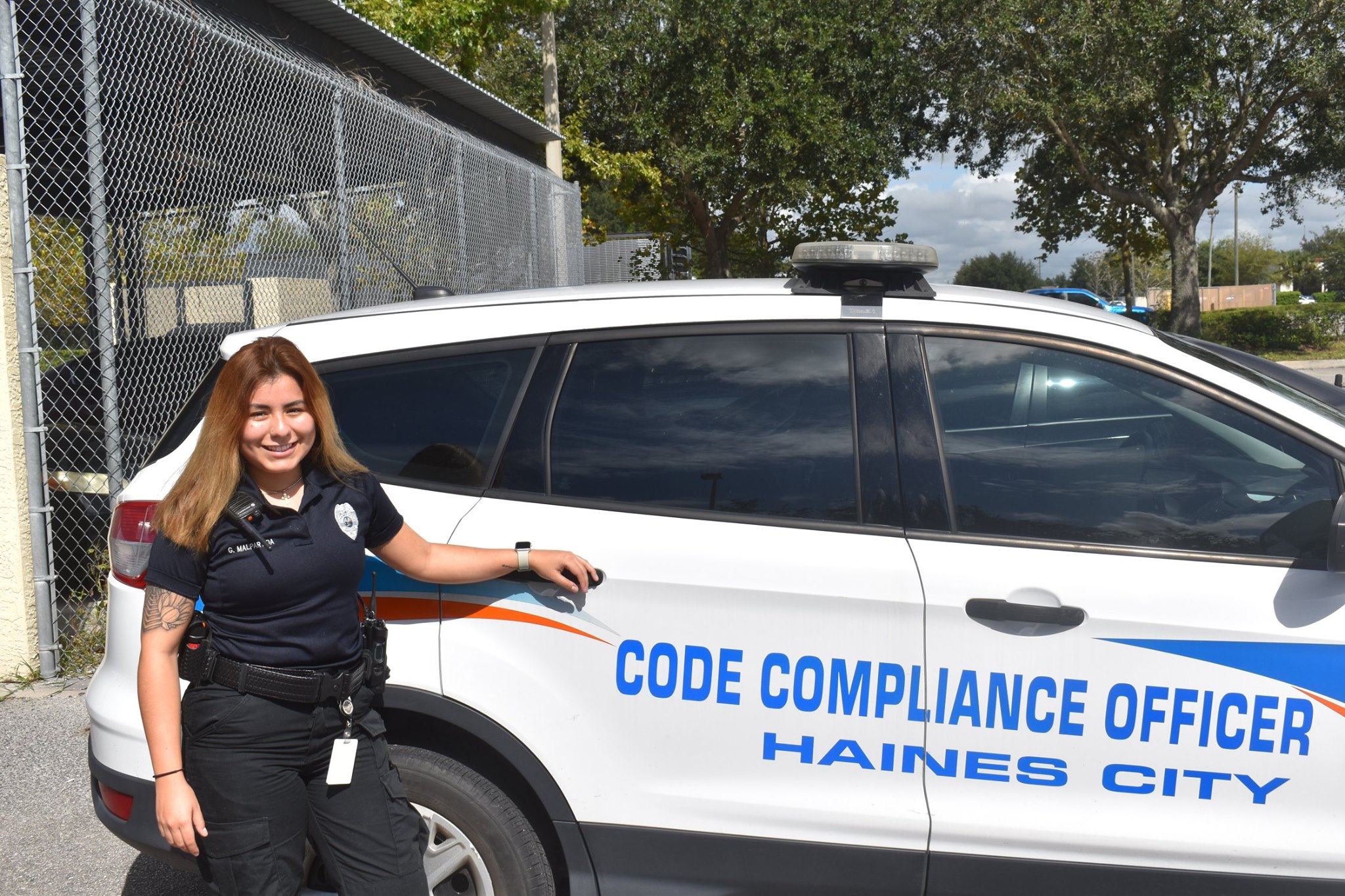Code Compliance Officer Grace Malpartida stands outside her vehicle. 